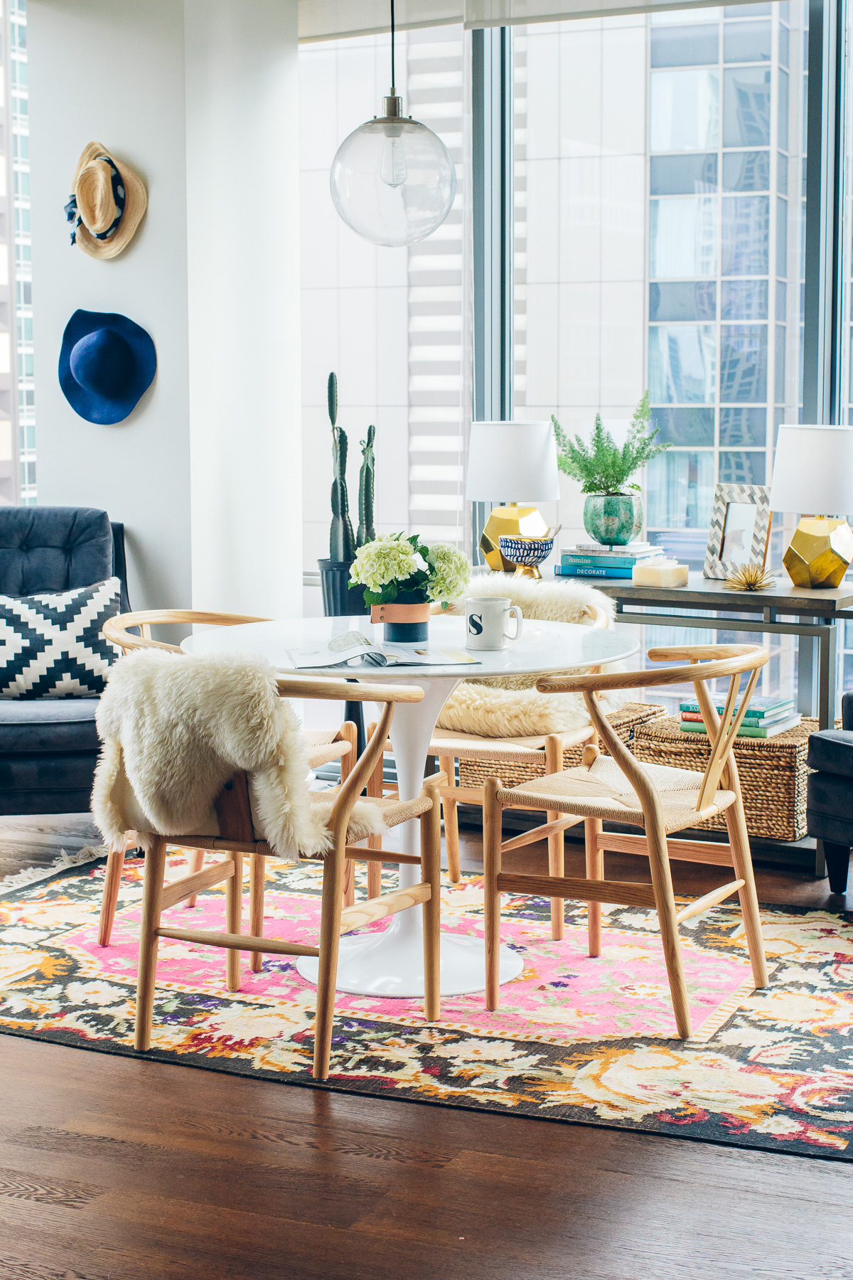 eclectic dining room with a bright and colorful woven rug, wishbone chairs and a marble tulip table—the perfect small space for hosting and living
