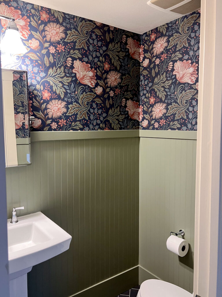 powder bath design with green beadboard and floral wallpaper